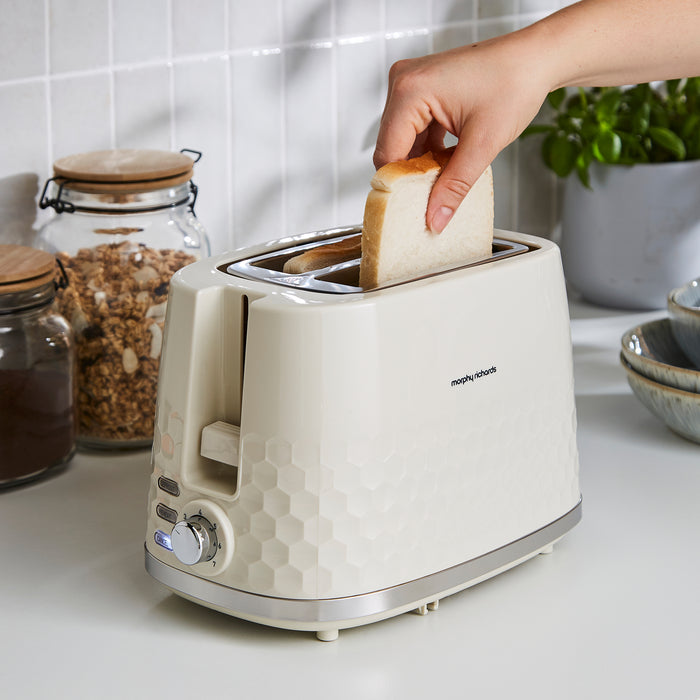 Person placing bread into a cream toaster on a kitchen counter.