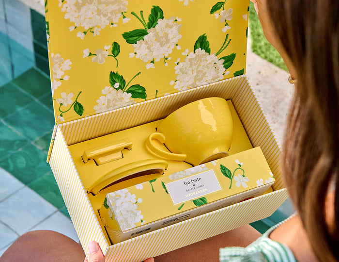 MAIN PDP | A woman opening a Hydrangea Gift Set, exposing all items within the box