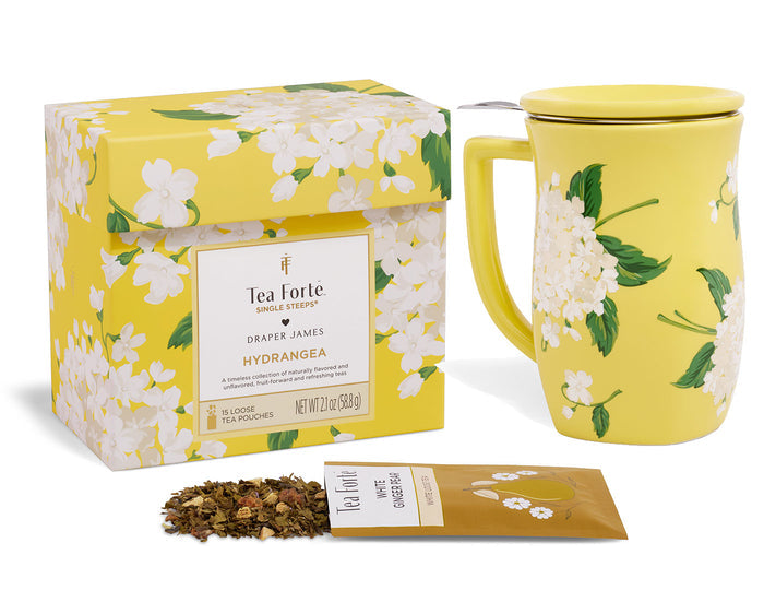 Yellow box with white hydrangea floral pattern, matching yellow mug with lid, and loose tea pouch with dried tea leaves.