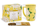 Yellow box with white hydrangea floral pattern, matching yellow mug with lid, and loose tea pouch with dried tea leaves.