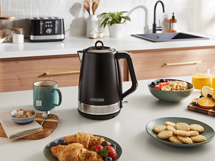 Black electric kettle on a kitchen counter with food and drinks
