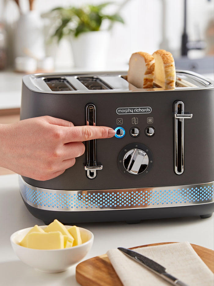 Person adjusting a Morphy Richards toaster with slices of bread inside, on a kitchen counter.