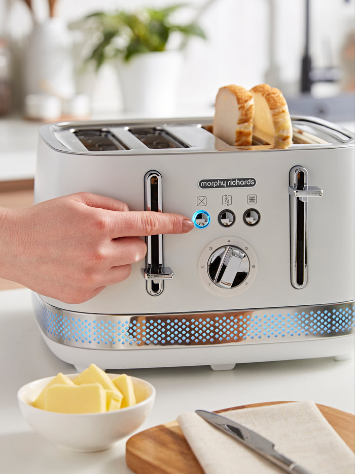 Morphy Richards toaster with bread being inserted, surrounded by kitchen items.