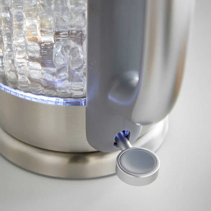 Close-up of a glass electric kettle with a metallic base and handle on a light background
