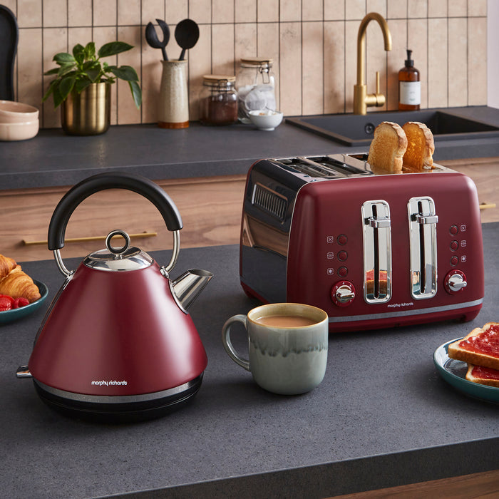 Red kettle and toaster on a kitchen counter with a cup of coffee and toast.