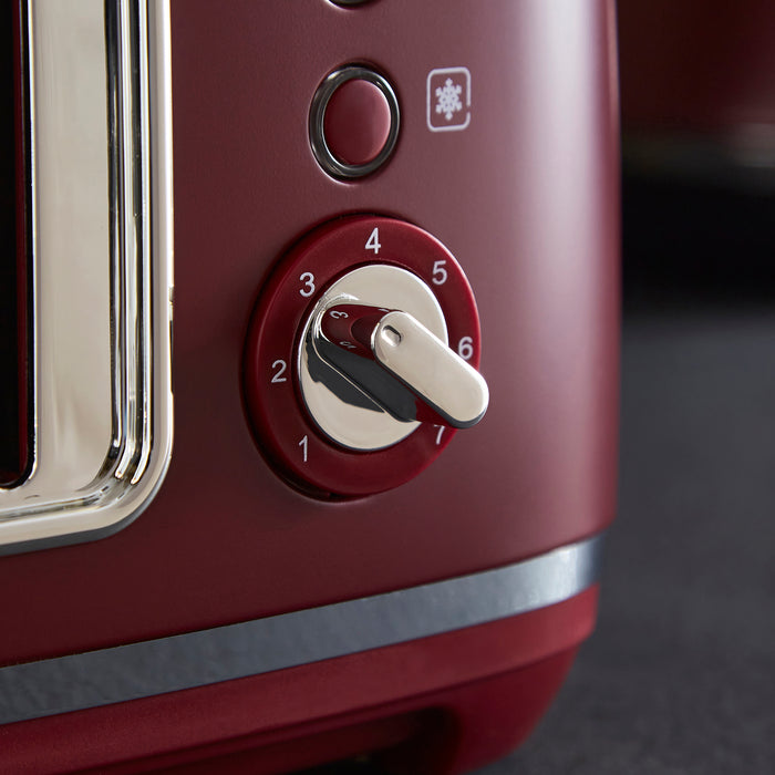 Close-up of a red toaster with control knobs on a dark background