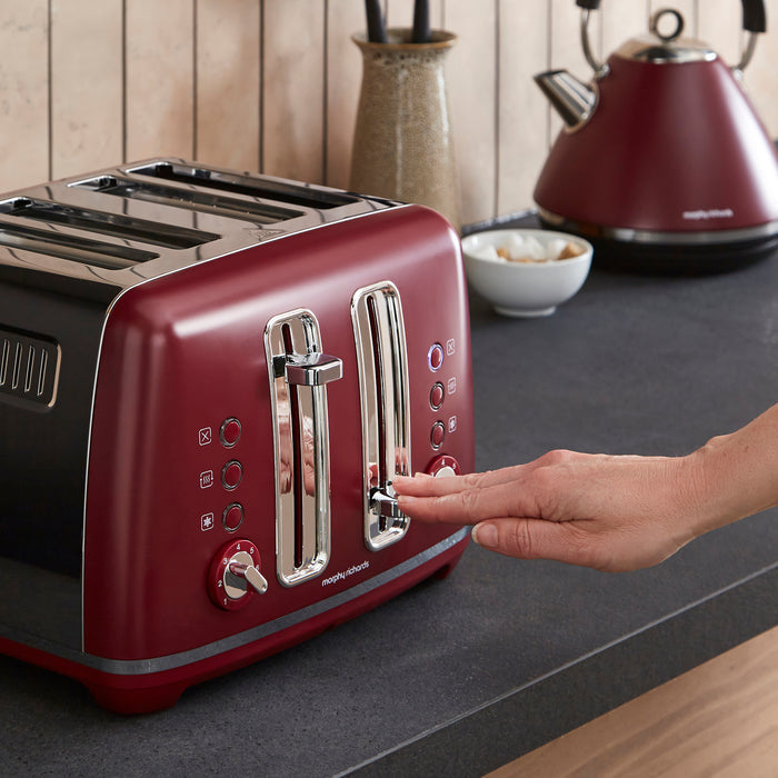 Red toaster on a kitchen counter with a hand pressing a button