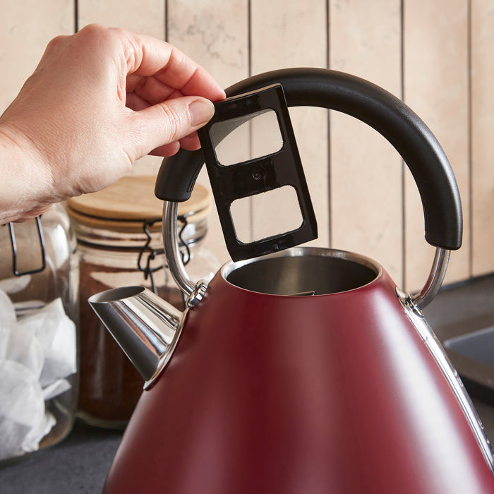Red kettle with a hand lifting the removeable limescale filter in a kitchen setting