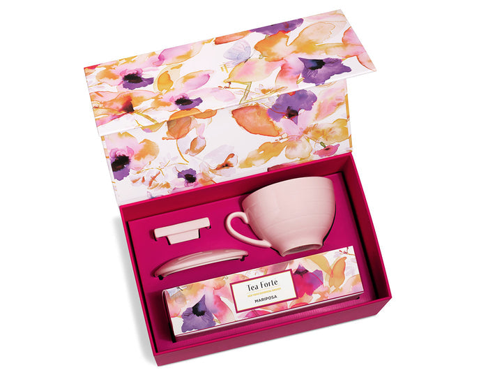 Pink gift box set containing ceramic cup with handle, spoon, and tea packet with floral watercolor design.
