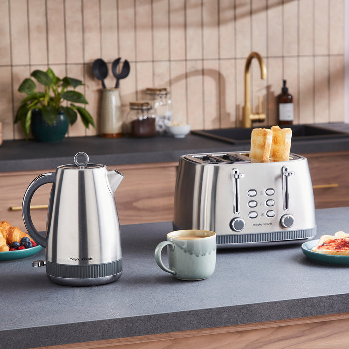 Kitchen counter with a silver kettle, toaster, and mug, with a blurred kitchen background.