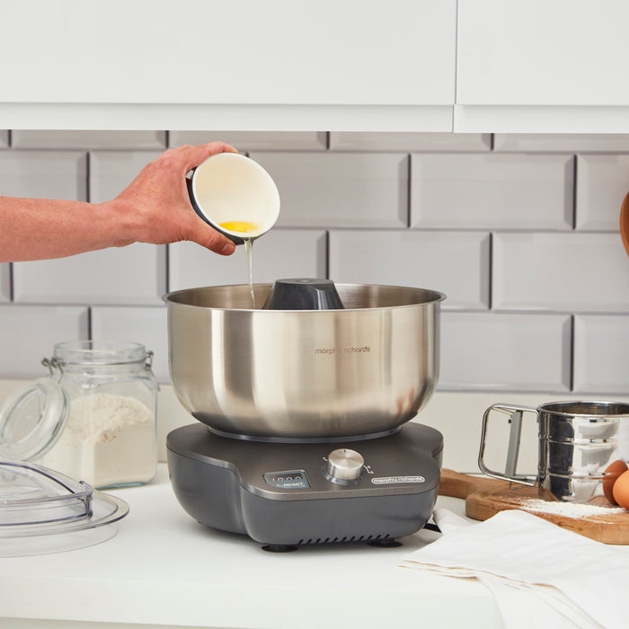 someone adding egg into the stand mixer