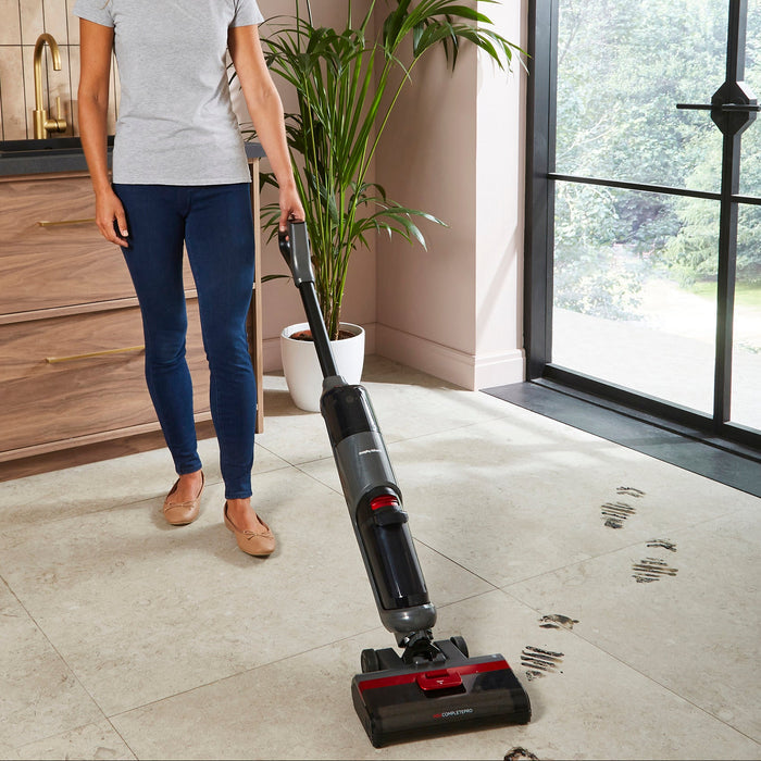 Woman using a Morphy Richards floor cleaner on a tiled floor in a kitchen.