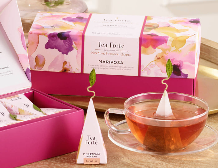 MAIN PDP | Mariposa Presentation Box of 20 pyramid tea infusers,  closed box o a table with a glass cup of tea and other boxes and infusers