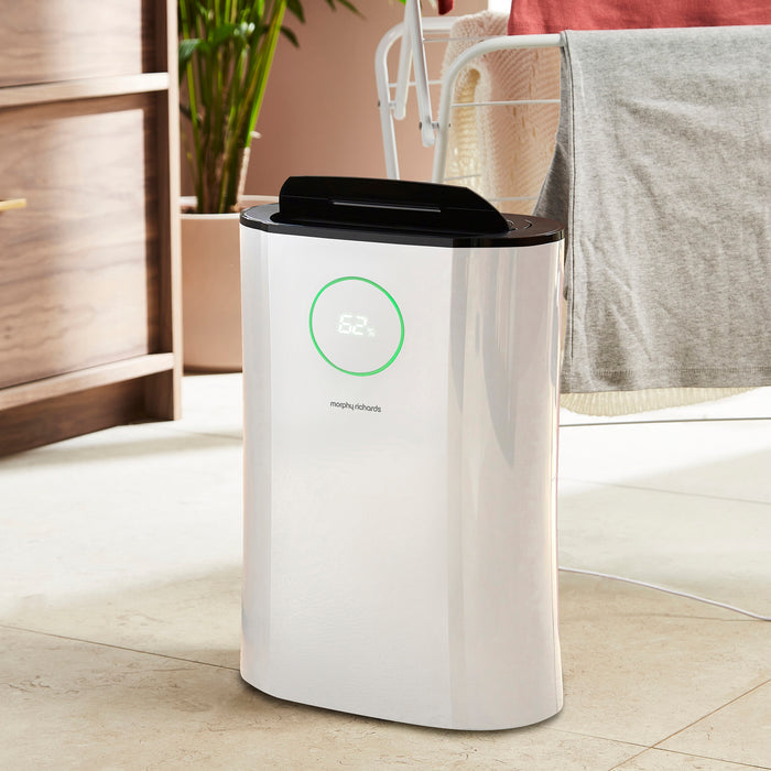 White dehumidifer with black top on a light wooden floor.