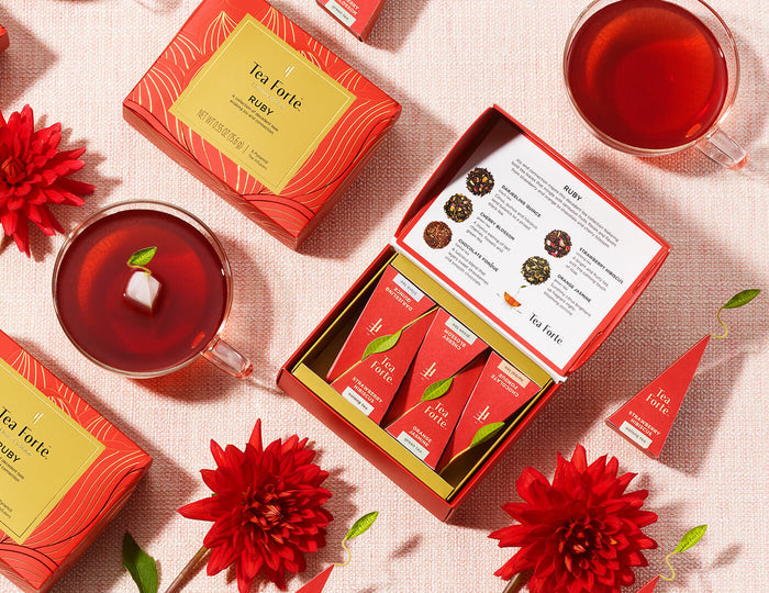 MAIN PDP | Ruby Mini Petite Box of 5 teas, open and closed on a table with cups of tea and pyramid infusers