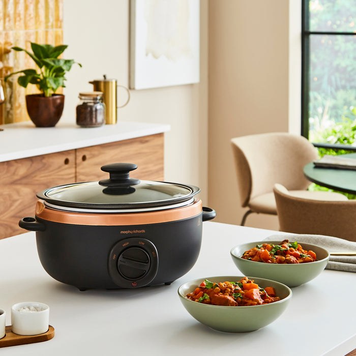 slow cooker on kitchen counter with bowls of food around it