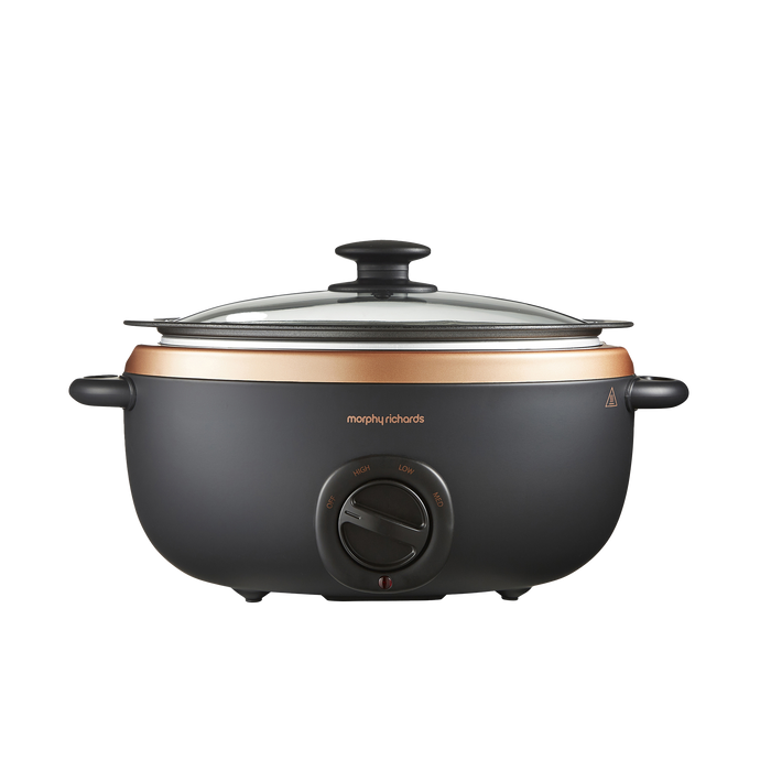 A rose gold and black slow cooker with a glass lid and analog control dial, featuring a hob-proof cooking pot.