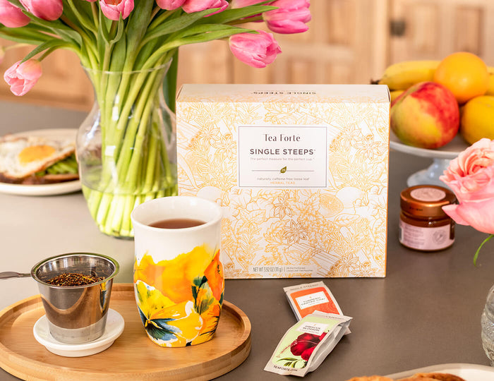 MAIN PDP | 28 count tea chest of Herbal Single Steeps pouches, lid closed, with tulips, breakfast food and Fiore Steeping Cup. Photo by @foodie_renee.