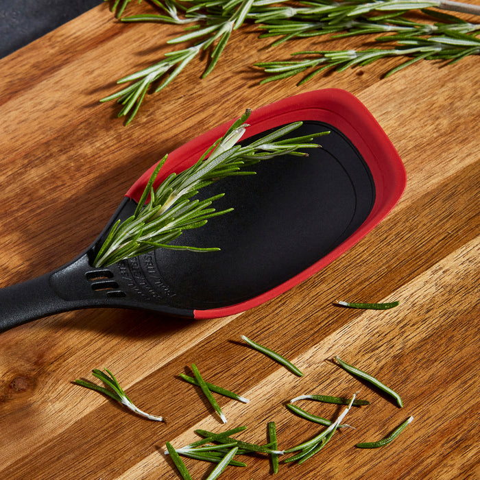 Black and red spatula with rosemary on a wooden surface
