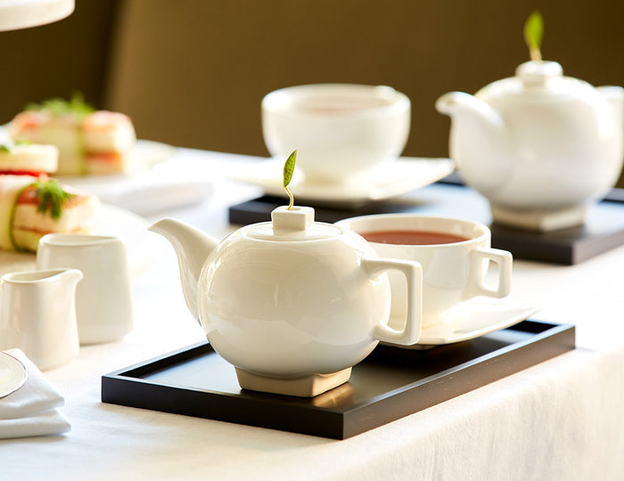 MAIN PDP | Solstice teapot with tea cup on a black tray on a dining room table