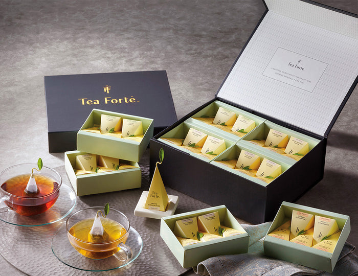MAIN PDP | Tea Forté Select Chest of 40 pyramid tea infusers, open  on a table with glass teacups