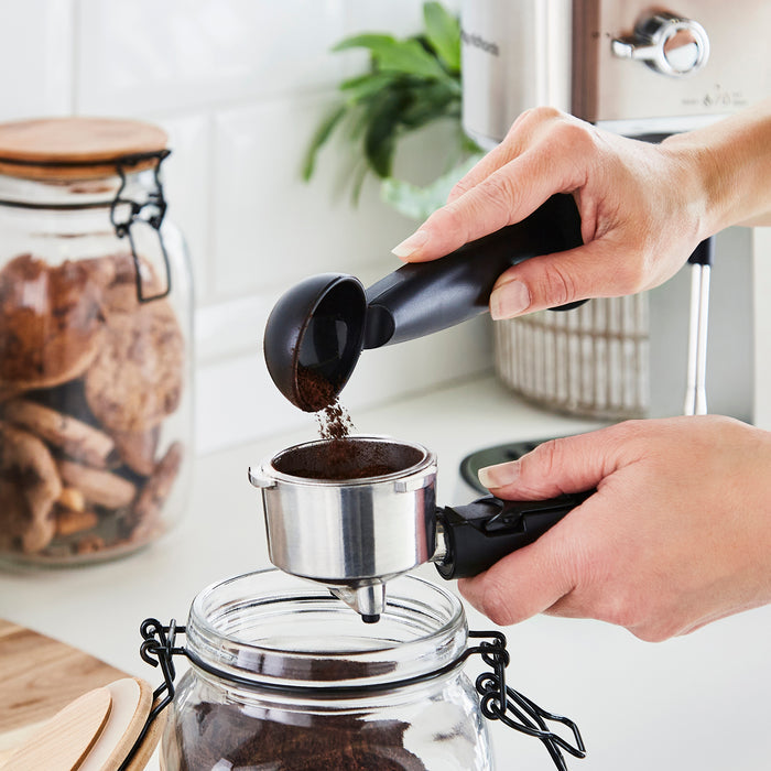 someone filling a porta filter with ground coffee