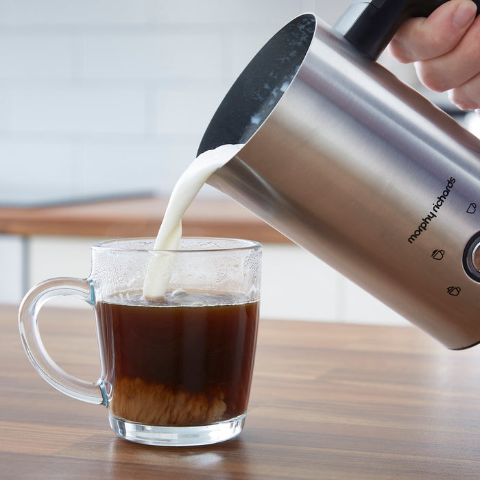 milk pouring from a milk frother into a cup of coffee