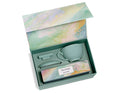 Open gift box containing a gray ceramic mug, tea infuser, spoon, and Tea Forte Wellbeing tea package with watercolor design.