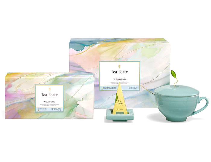 Tea Forte Wellbeing gift set with colorful boxes, tea pyramid, ceramic teacup with lid and leaf garnish.