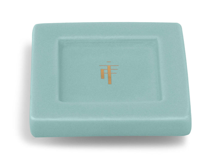 Light blue ceramic tray with gold logo and recessed center well.