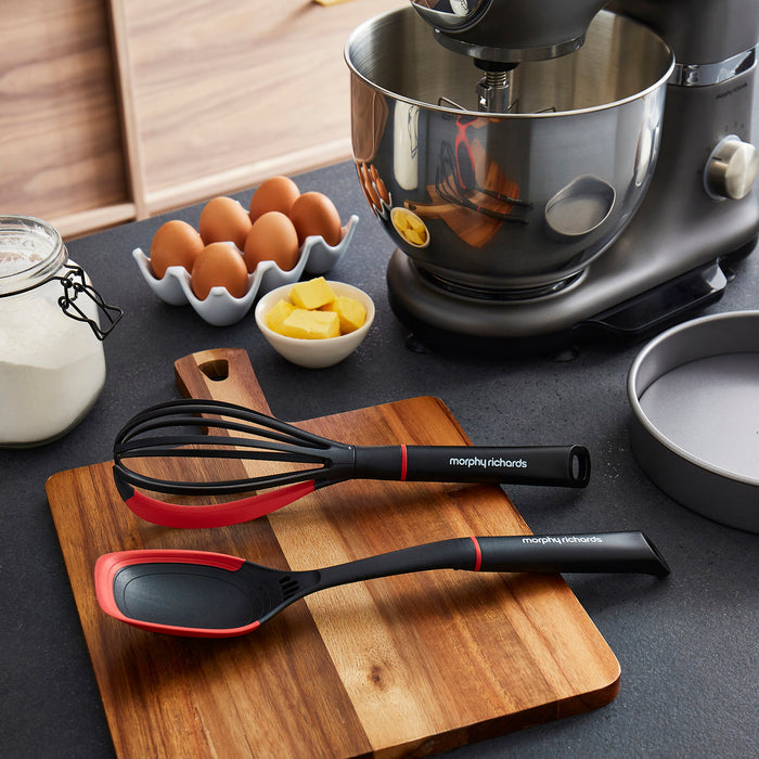 Whisk and Solid Spoon on a wooden chopping board