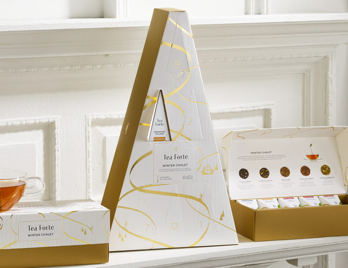 MAIN PDP | Winter Chalet Advent, with one door open, on a white shelf with other Winter Chalet products